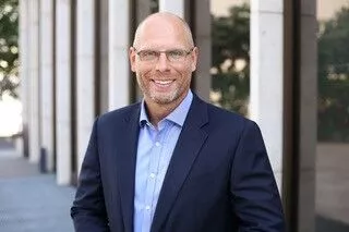 a man in a suit and glasses standing in front of a building